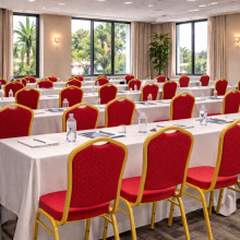 Konferenční židle s červeným čalouněním a zlatým rámem.